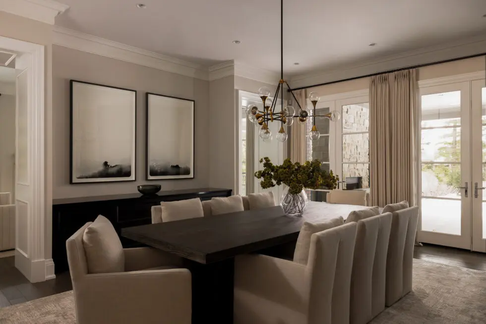 Elegant modern dining room with a long dark wood table, beige upholstered chairs, and a black and brass Sputnik chandelier.