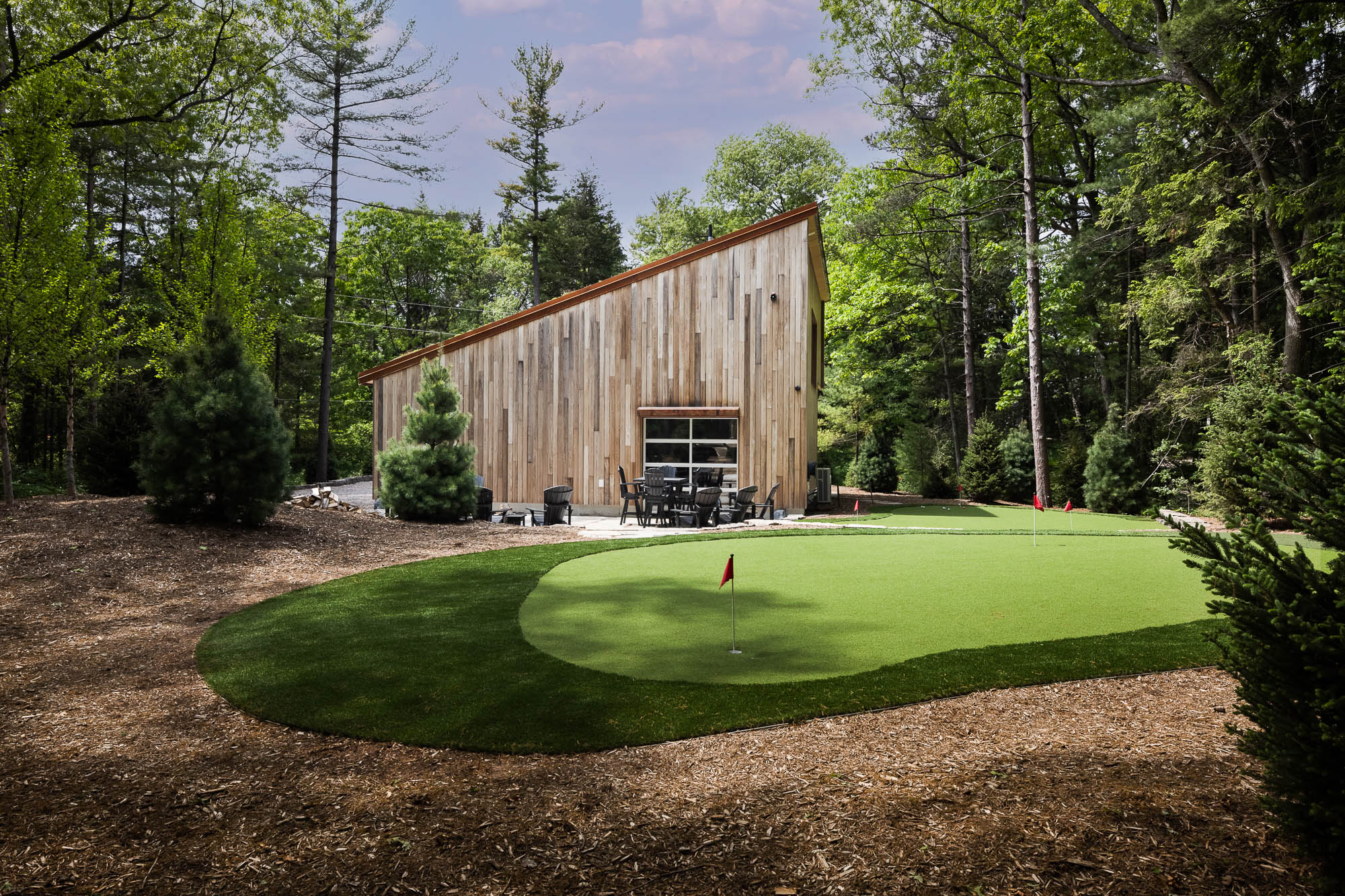 Modern Wood Siding and Backyard Putting Green Architectural photography of a contemporary wood-clad building with a sloped green roof next to a backyard putting green.