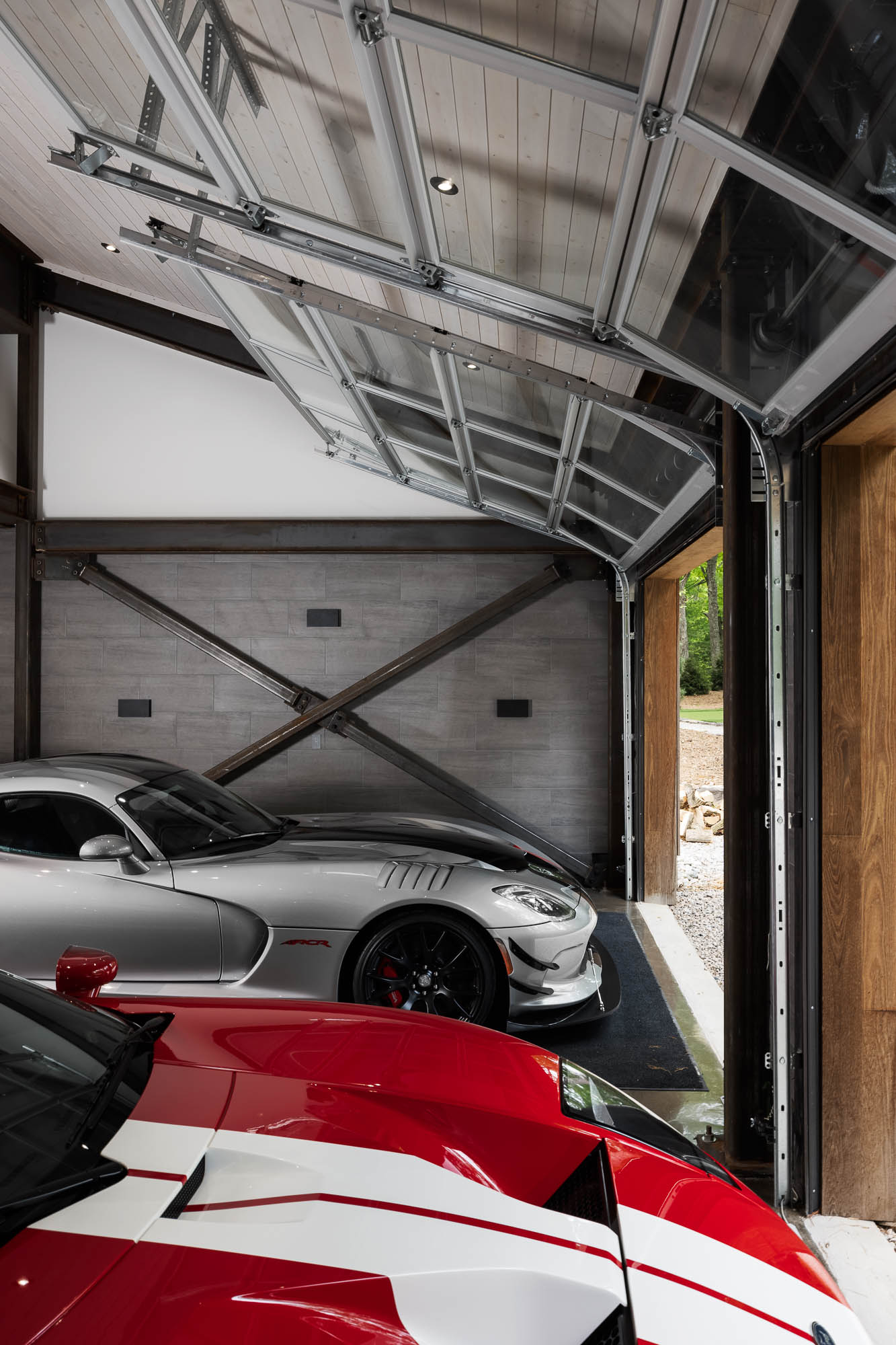 Industrial Garage Interior with Glass Doors Interior view showing glass-paneled overhead garage doors and exposed steel cross-bracing with a silver Dodge Viper.