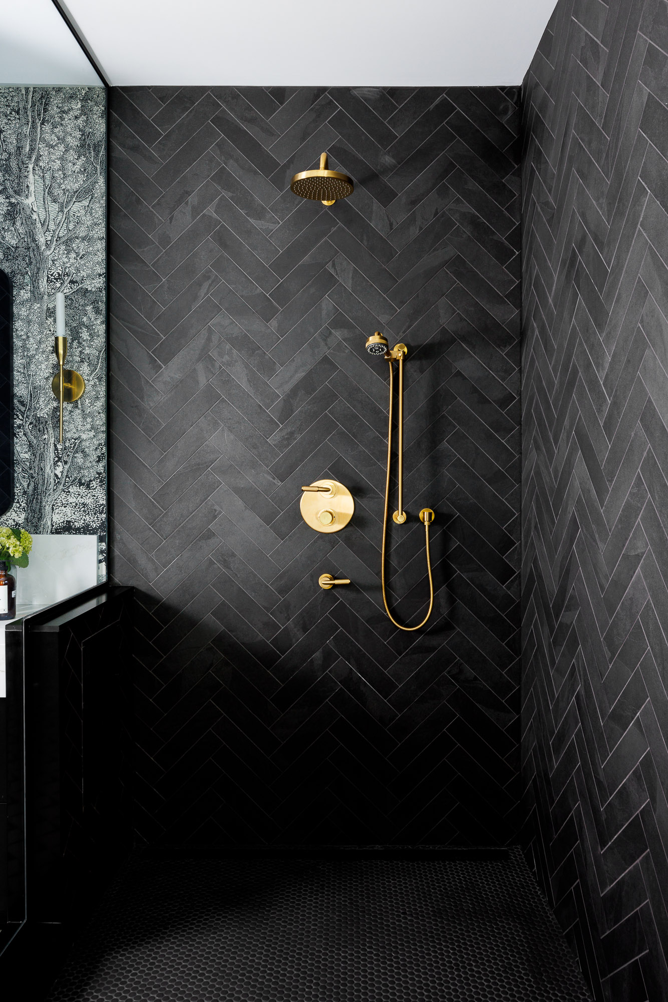 black-herringbone-tile-gold-shower-master-suite Modern master bathroom featuring black herringbone wall tiles, brushed gold shower fixtures, and black penny floor tiles in a villa.