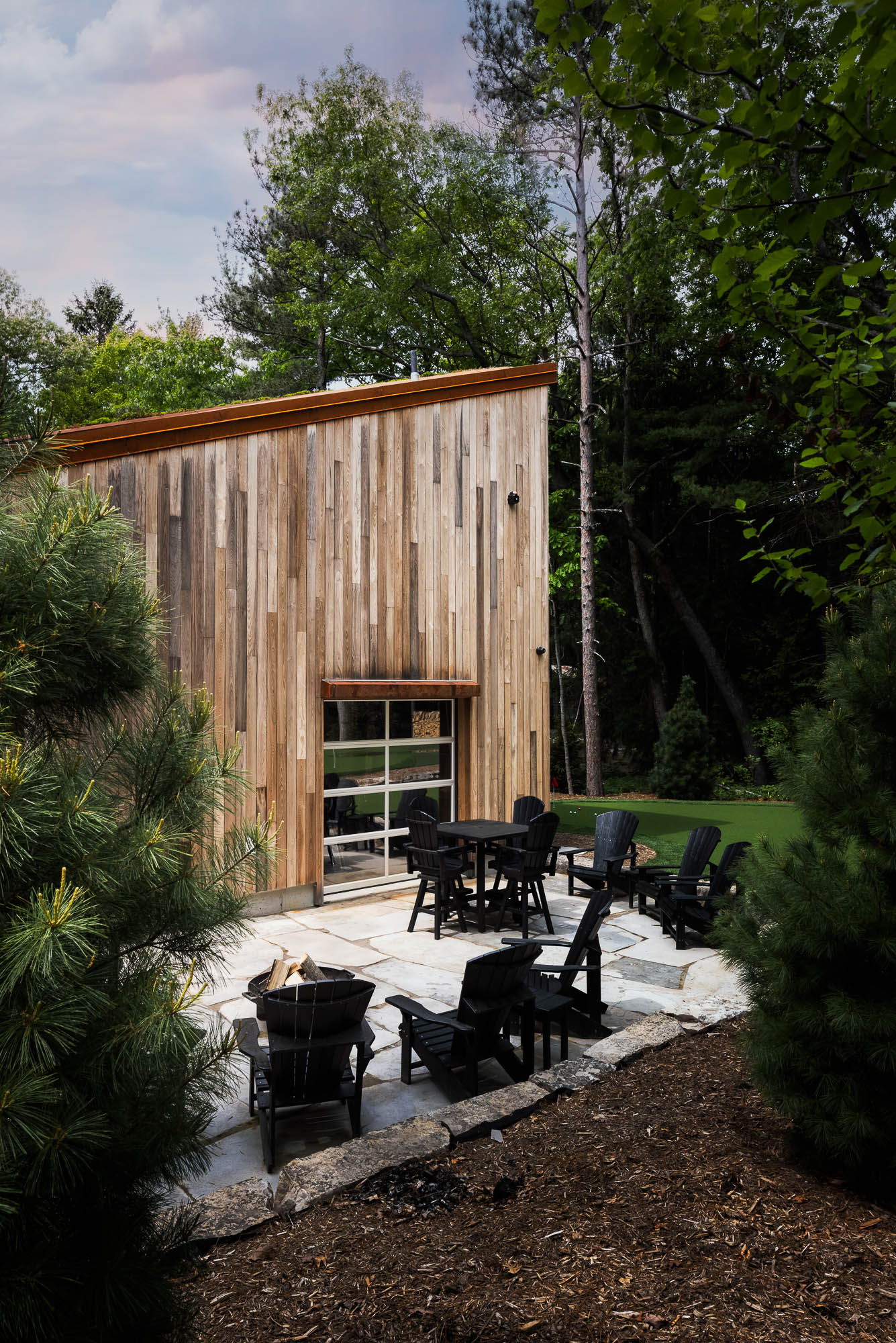 Modern Patio and Glass Garage Door Vertical architectural photograph of a stone patio and black seating area next to a translucent glass garage door.