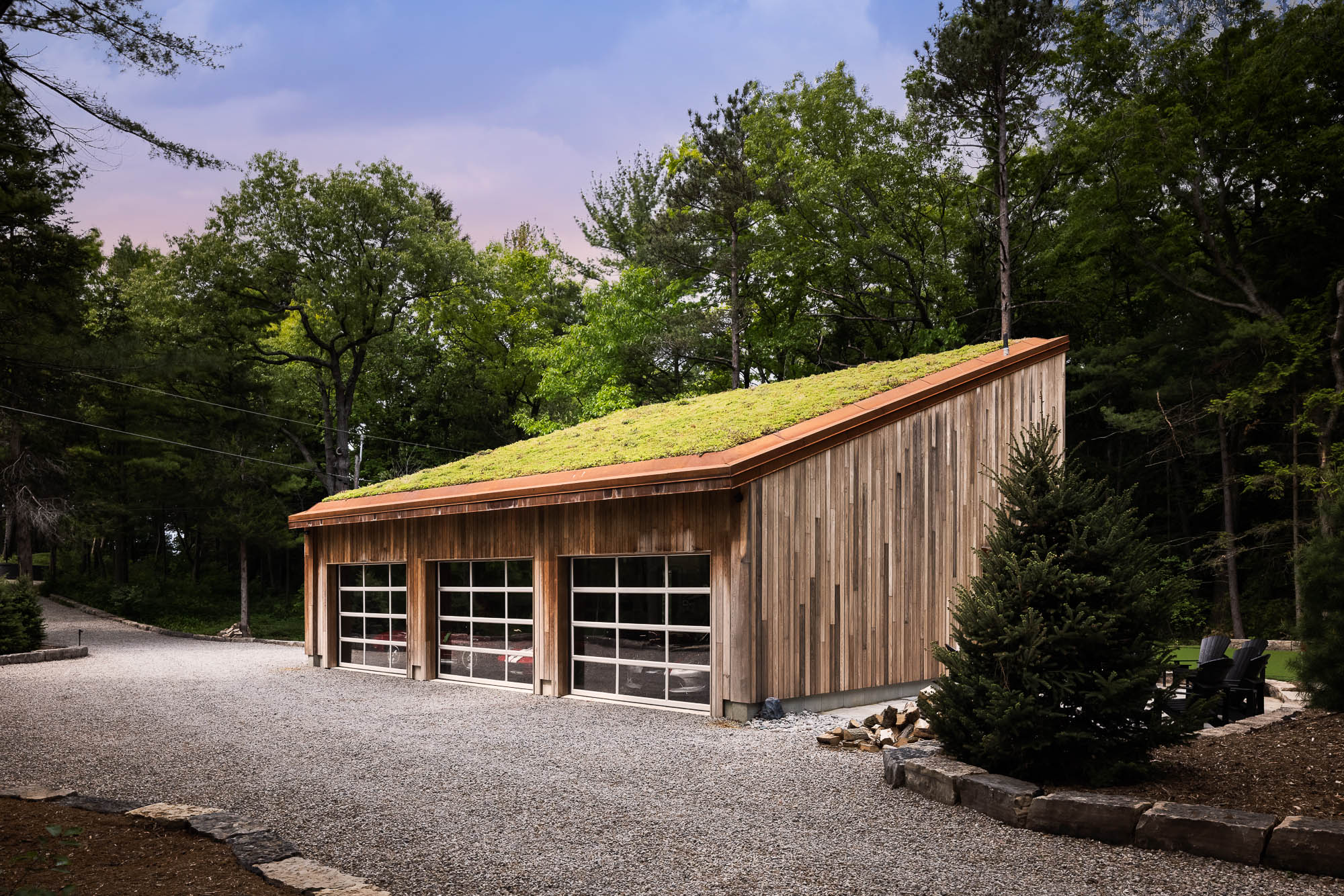 Three-Bay Garage with Sedum Green Roof Exterior shot of a modern three-bay garage with translucent glass doors and a vibrant green sedum roof.