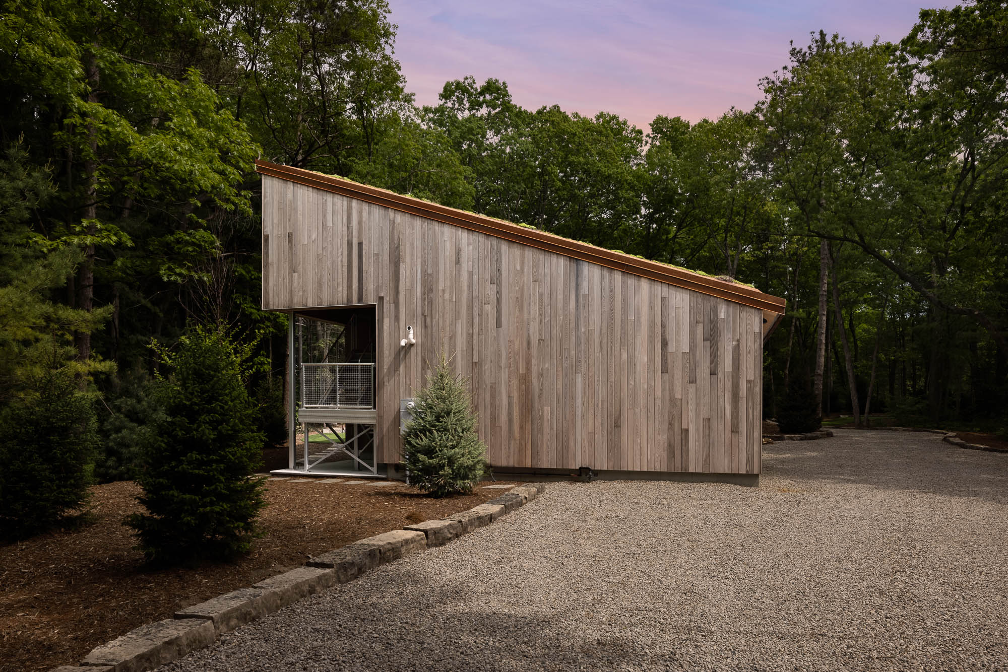 Contemporary Profile and Cantilevered Deck Side view of a modern wood building showing the sloped roofline and a cantilevered metal balcony.