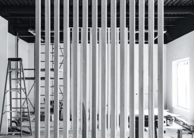 Black and white image of a modern wooden slat partition wall in an unfinished commercial interior under construction.