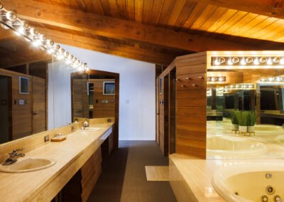 Luxury bathroom with wood ceiling, exposed beams, double vanity, and large jacuzzi tub with mirrors.