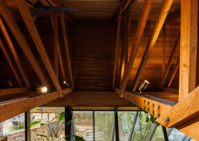 High-angle view of a modern multi-level home interior with exposed wooden beams, stone floor, and large glass windows.