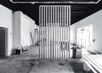 Black and white interior of a commercial space under construction with a modern slatted room divider.