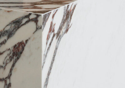 Close-up of polished white marble with striking reddish-brown and grey veining at a corner