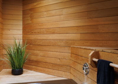 Modern bathroom with brown corner bathtub, natural wood paneling, skylight, and a green plant