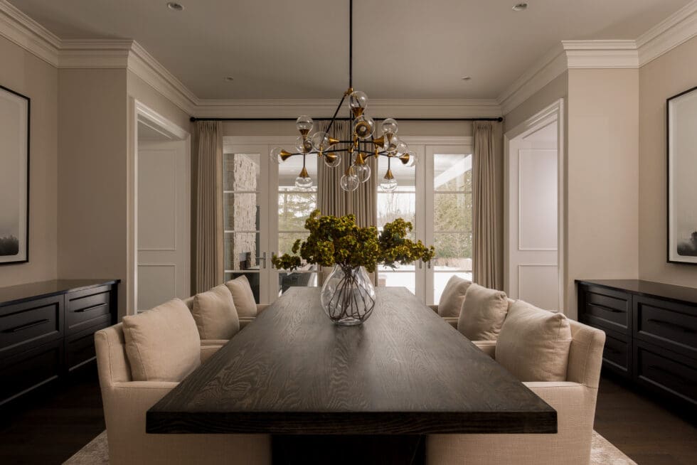 Elegant modern dining room featuring a dark wood dining table, beige upholstered chairs, and a contemporary glass globe chandelier.