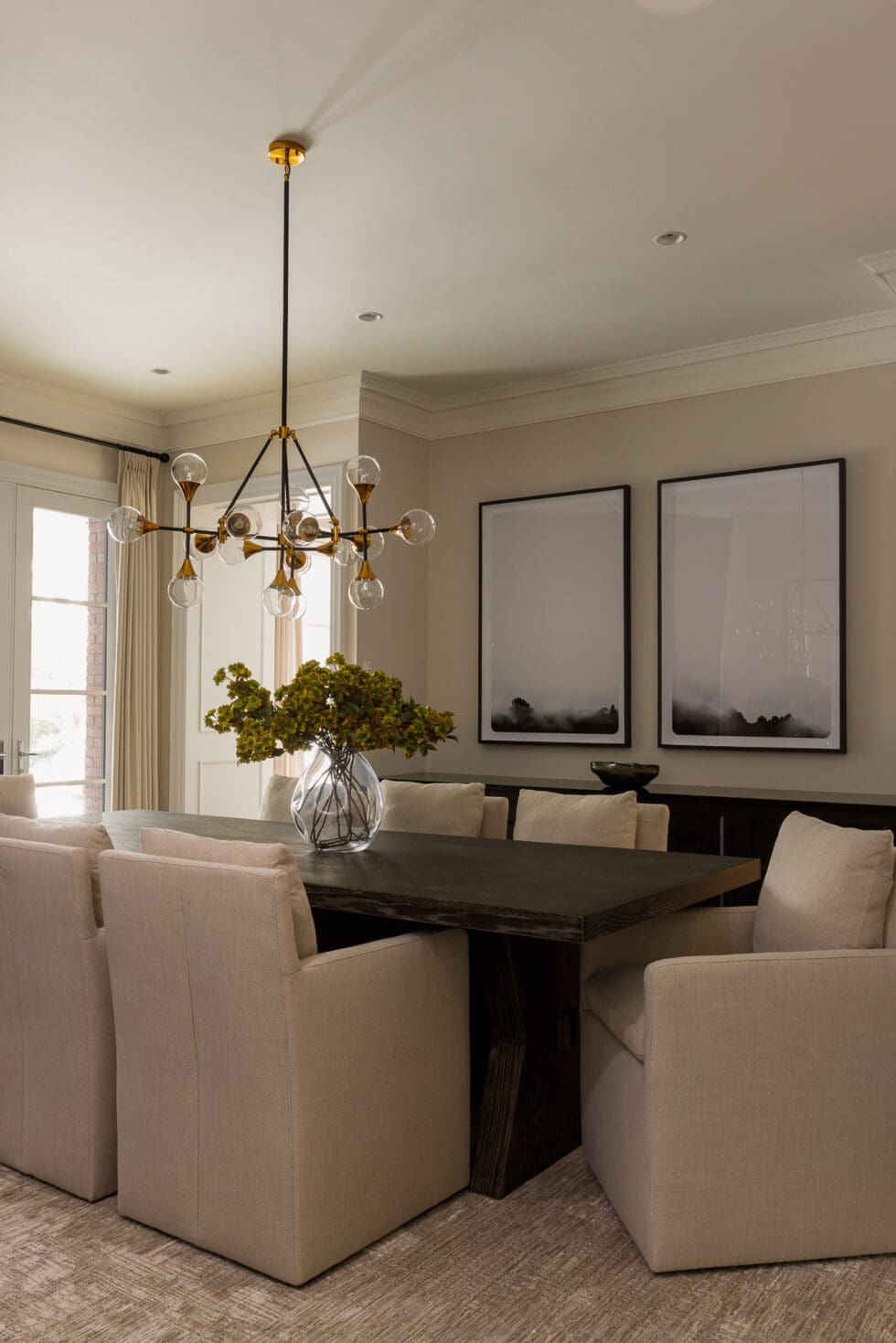 Elegant modern dining room with a dark wood table, neutral upholstered chairs, and a striking brass and glass chandelier