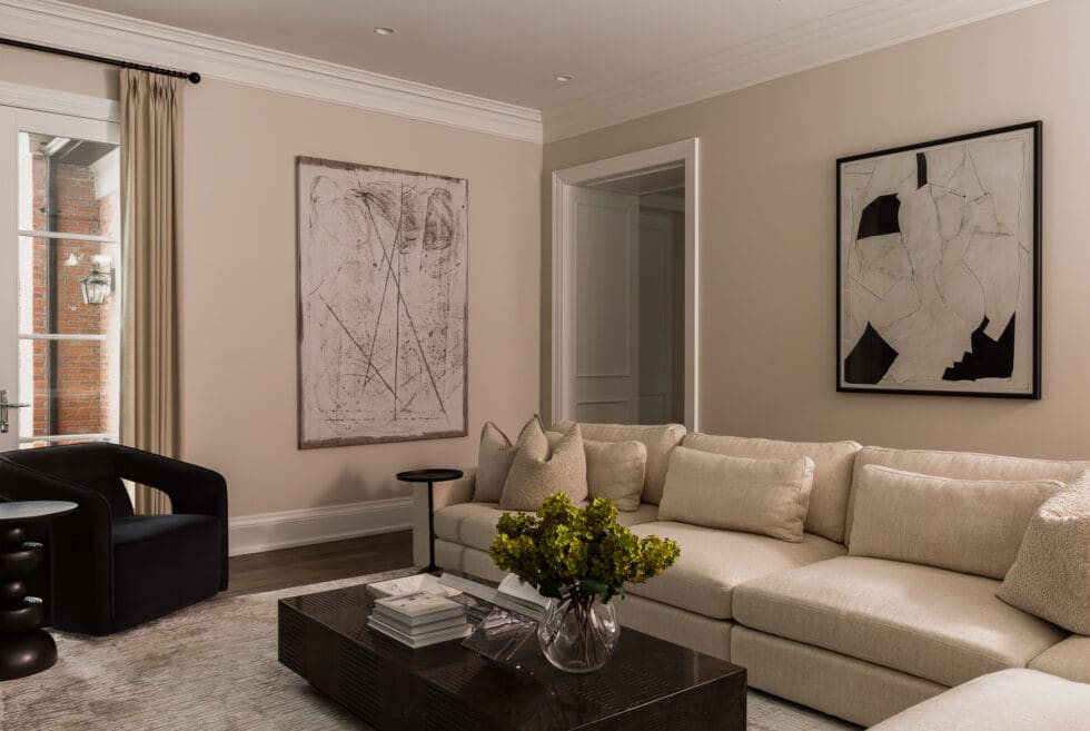 Elegant modern living room with a neutral sectional sofa, abstract art, and dark wood coffee table.