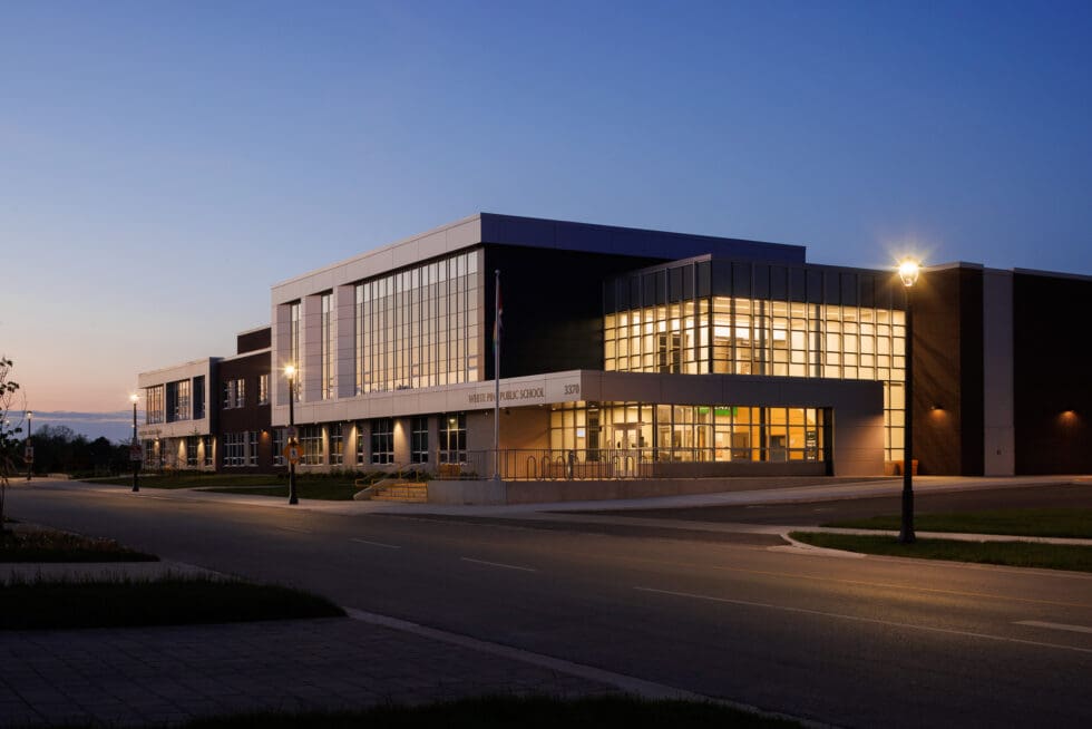 White Pine Public School exterior at dusk, modern building with lights on